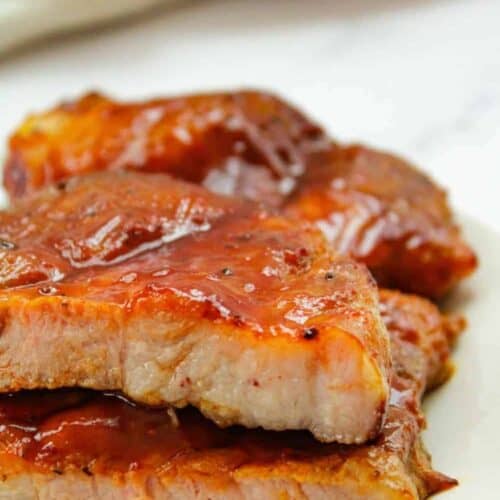 BBQ Air Fryer Pork Steaks on a white plate cut in half stacked on top of each other