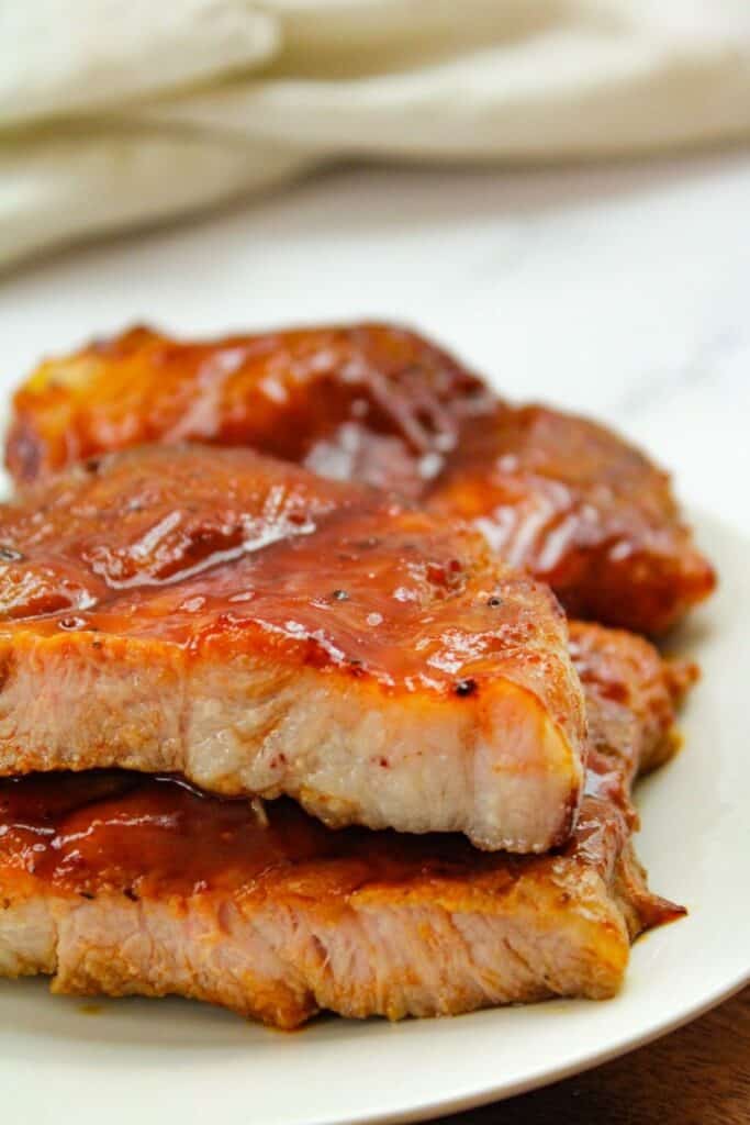 BBQ Air Fryer Pork Steaks on a white plate cut in half stacked on top of each other