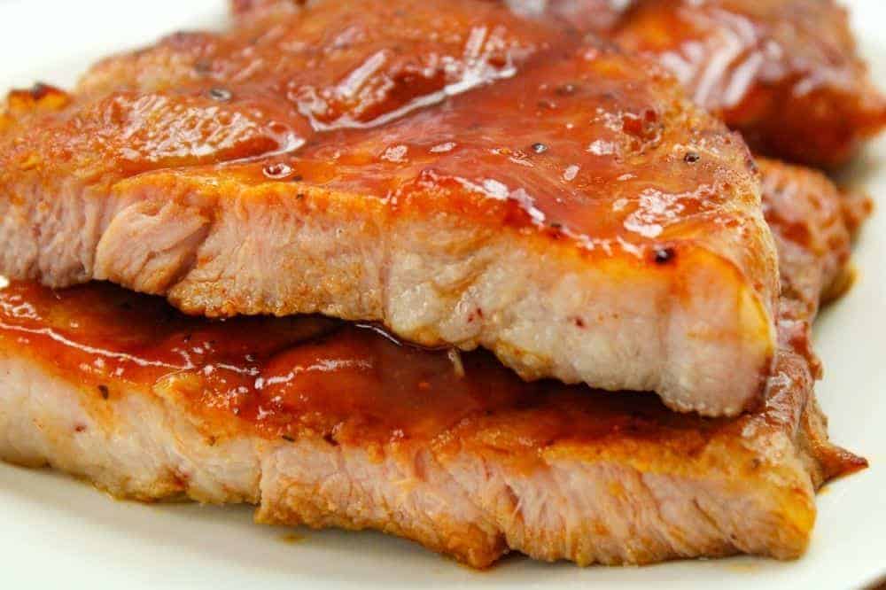 Closeup of air fryer pork steaks on a white plate cut open