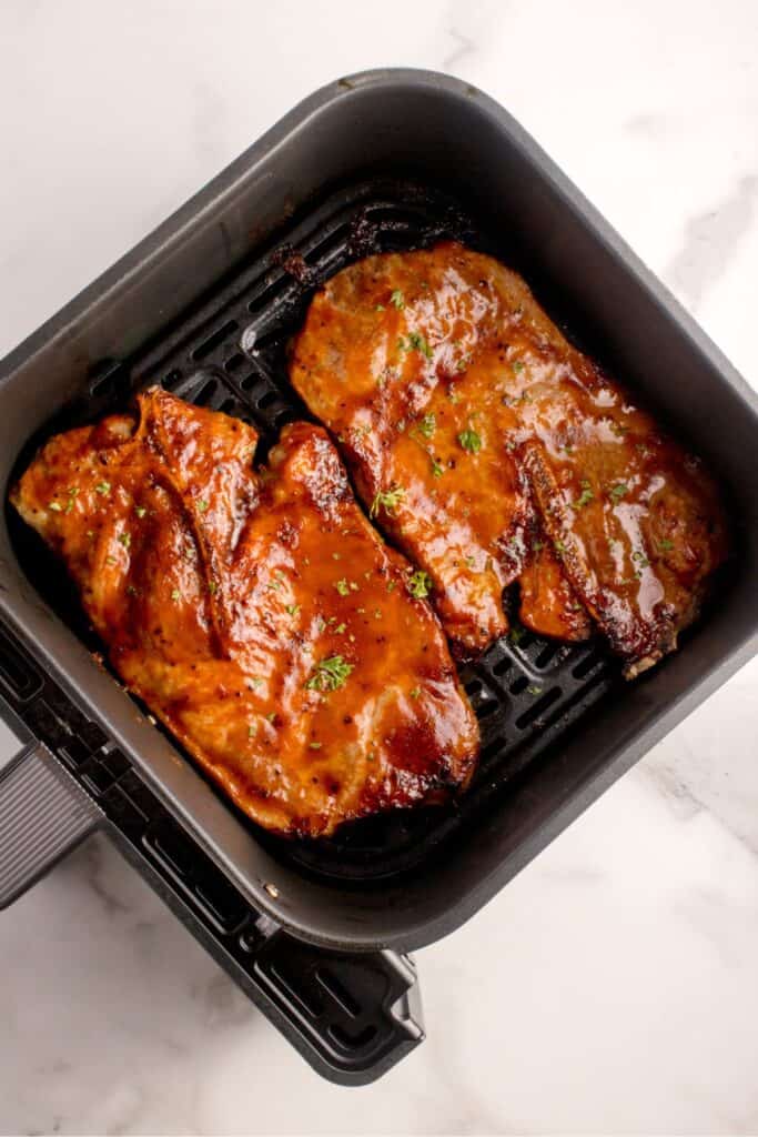 Cooked pork steak in an air fryer basket.