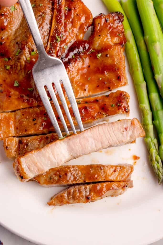 Air fryer pork steak cut into strips with a fork showing the inside of one of them.
