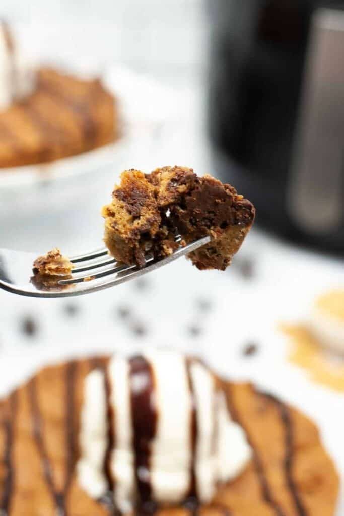 Closeup of a piece of cookie cake on a fork with full cookie cake in background