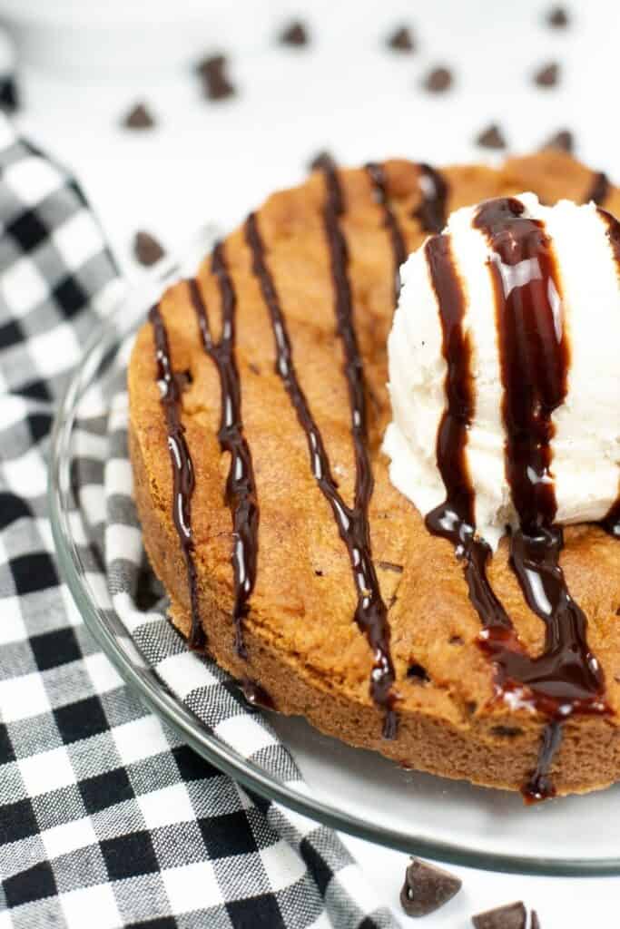 Closeup of half of the finished cookie made in the air fryer with ice cream and syrup on top