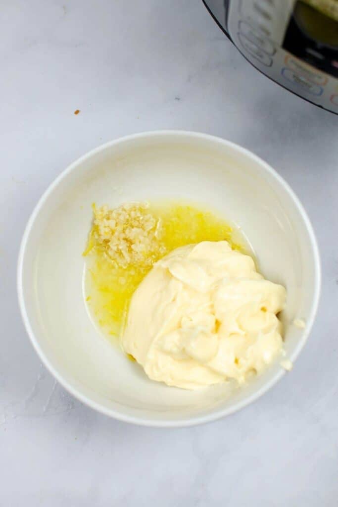 Aioli sauce ingredients added into a white bowl