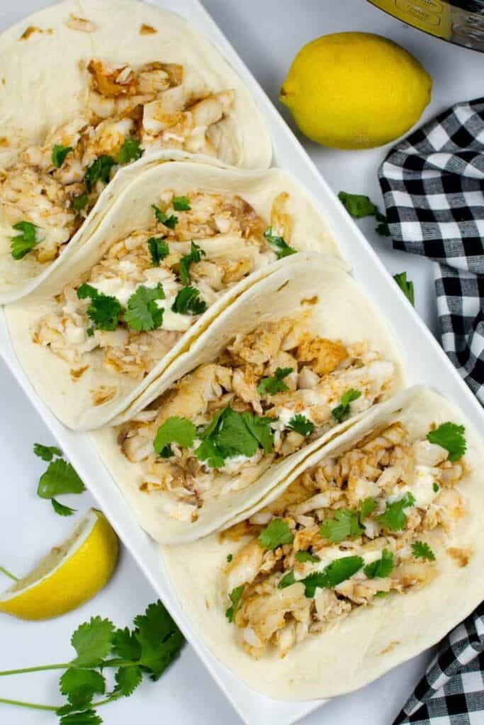 Instant Pot Fish Tacos on a white rectangular plate with cilantro on top