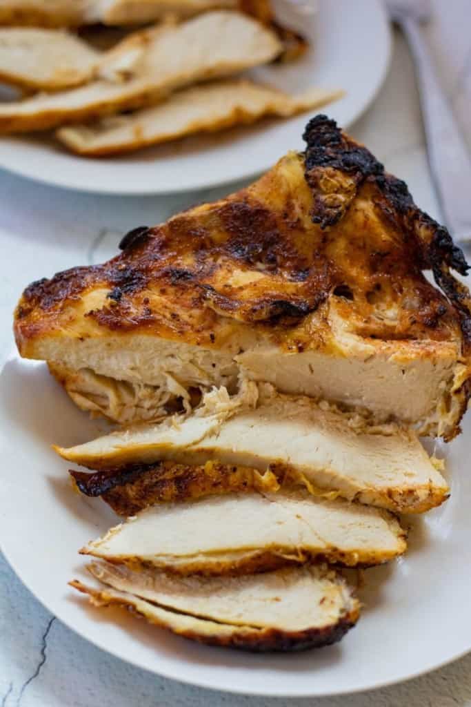 Air Fryer Split Chicken Breast on a white plate with slices cut out