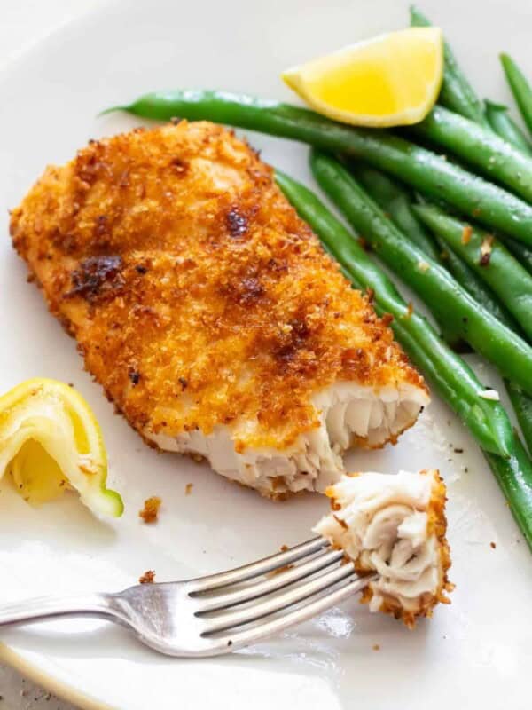 Air Fryer Mahi Mahi with a bite on a fork served with green beans and a slice of lemon