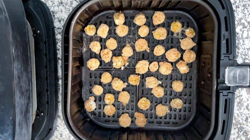 Breaded okra in an air fryer basket ready to be cooked.