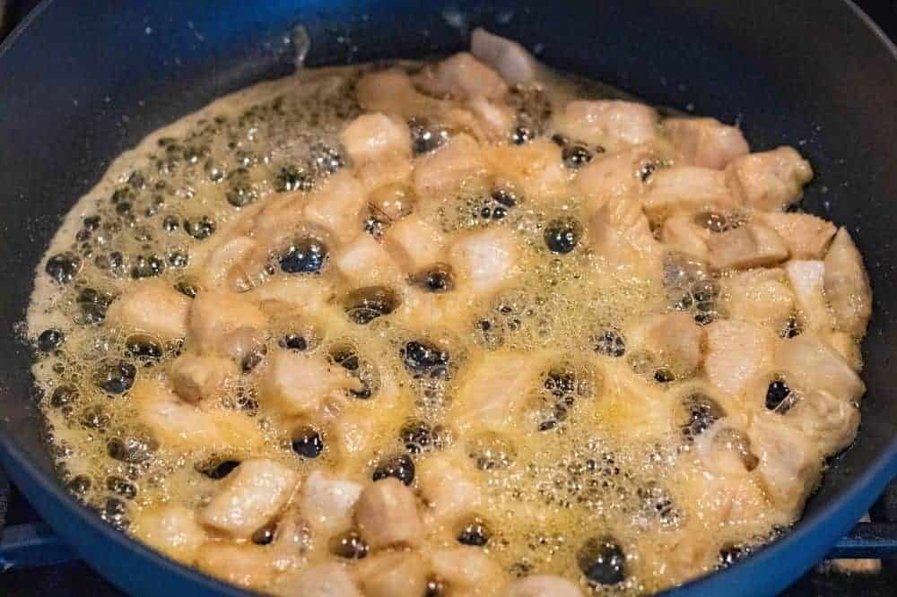 Chicken being cooked in honey and butter in a saucepan