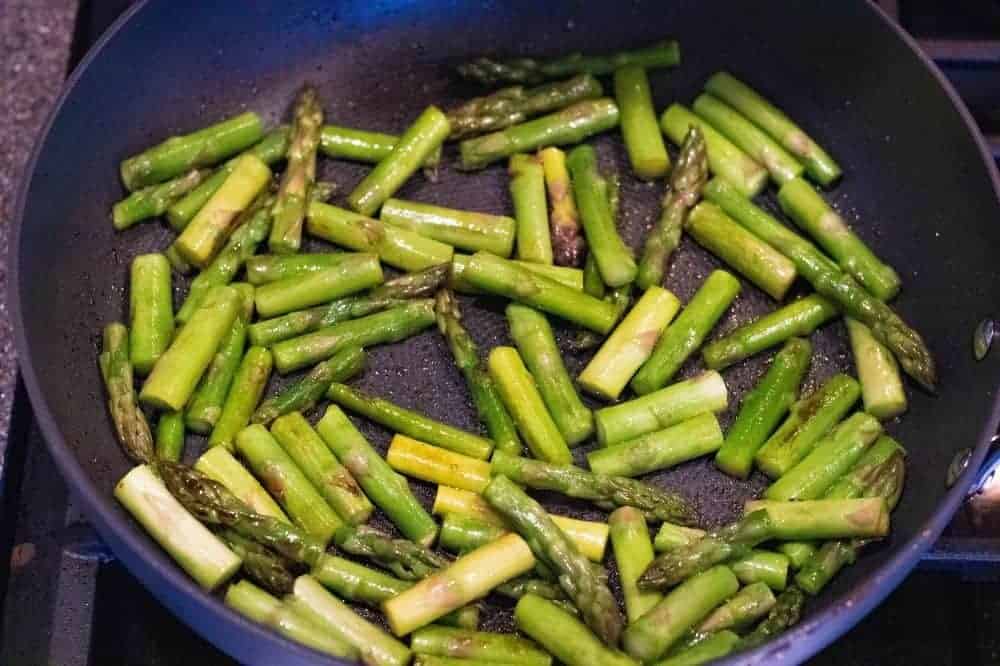 Asparagus and butter being cooked in a pan