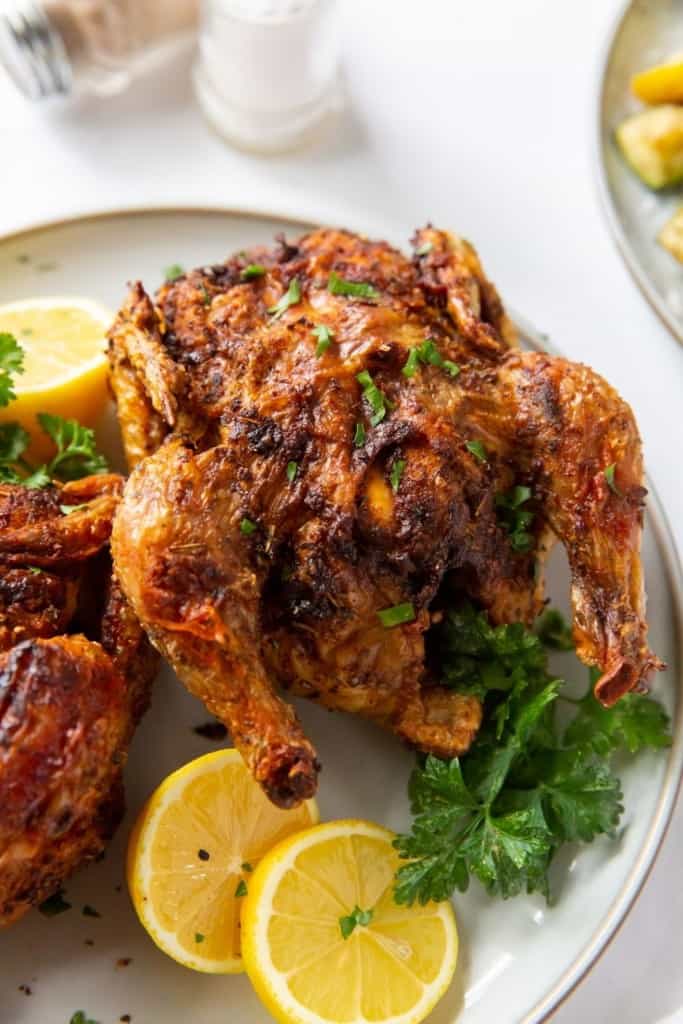 Closeup of one cornish hen served with lemon halves