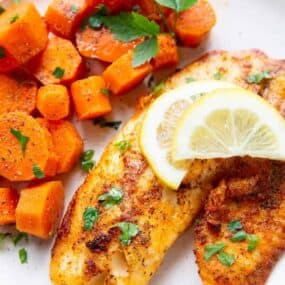 Air Fryer Tilapia with lemon sliced on top served with cooked chopped carrots