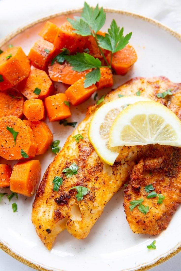 Air Fryer Tilapia with lemon sliced on top served with cooked chopped carrots