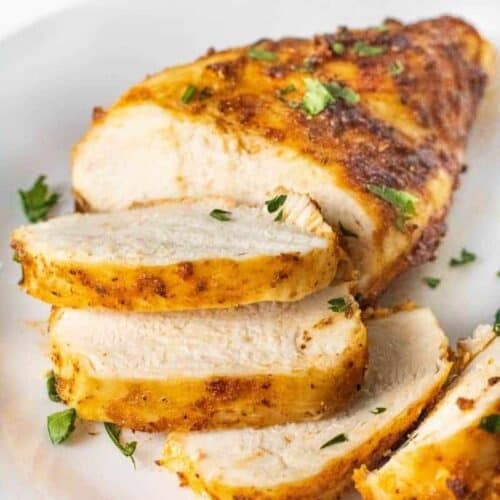 Closeup of sliced air fryer chicken breasts that were cooked from chicken on a white plate
