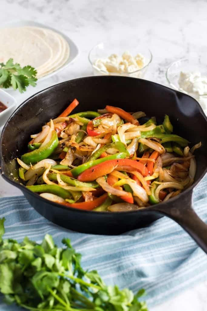 Sauteed peppers and onions inside a cast iron skillet