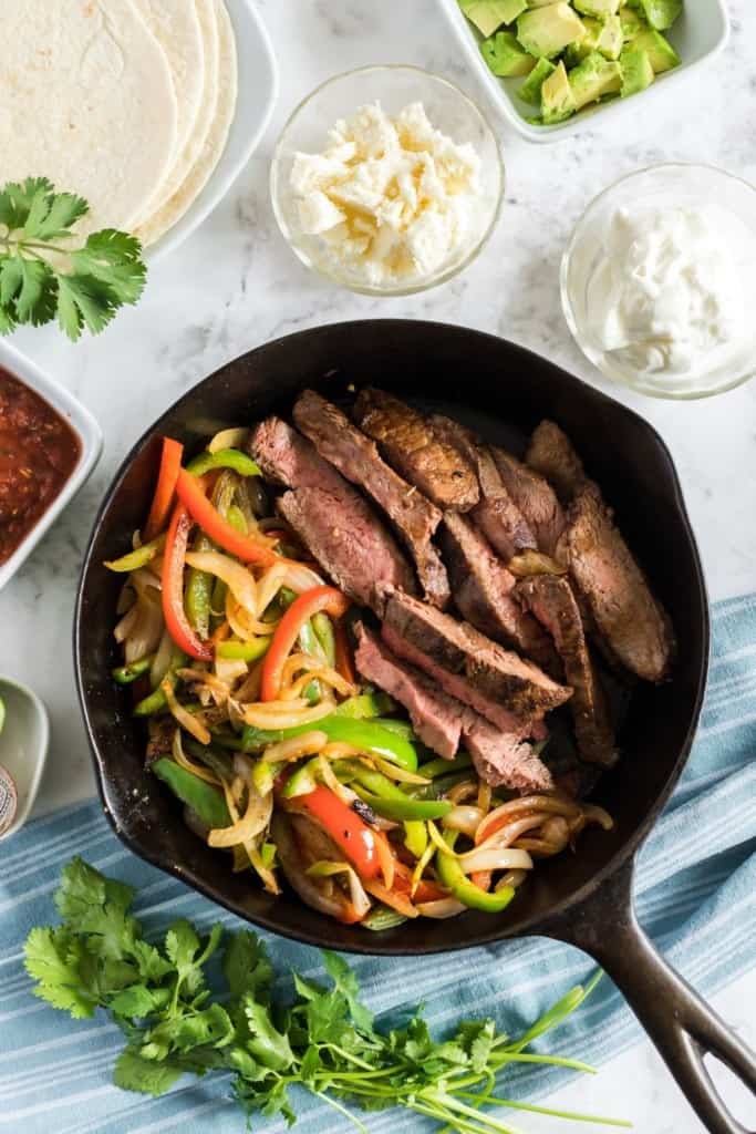 Leftover steak added to the cast iron skillet with the cooked peppers and onions