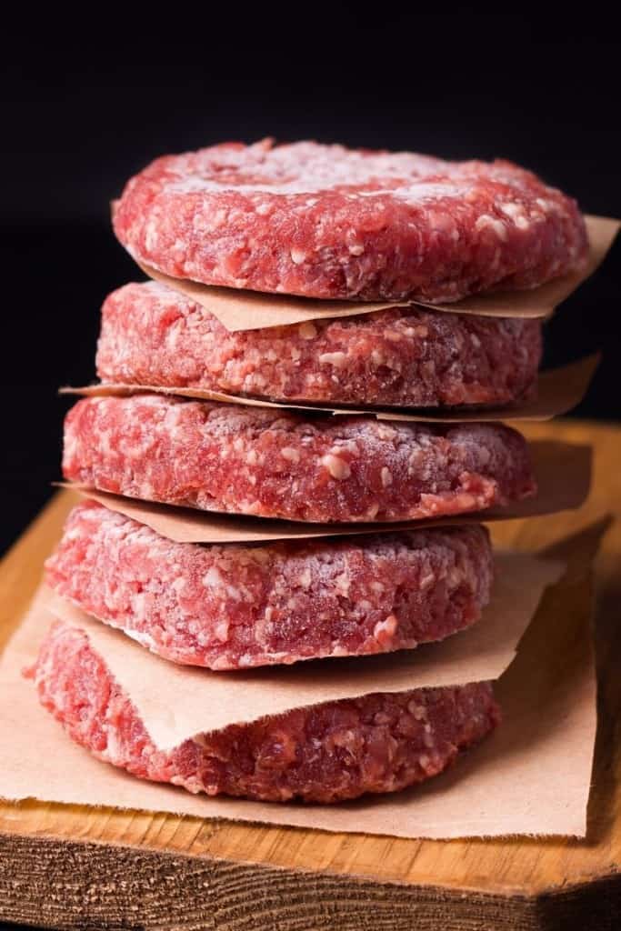 Frozen hamburgers stacked on top of each other with parchment paper in between them