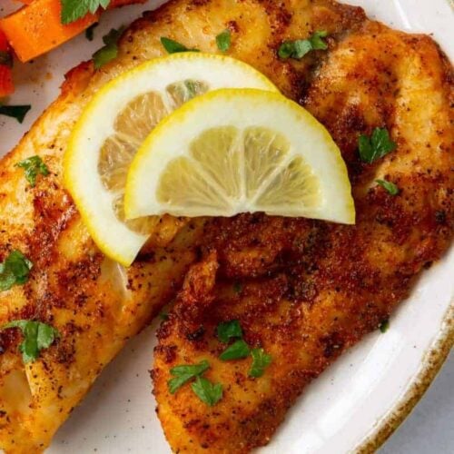 Air Fryer Tilapia on a plate with lemon wedges on top