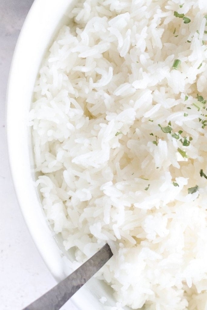 Jasmine rice inside a white bowl with a spoon in it