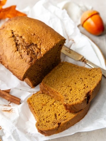 Cake mix pumpkin bread loaf with 2 slices cut laying on parchment paper