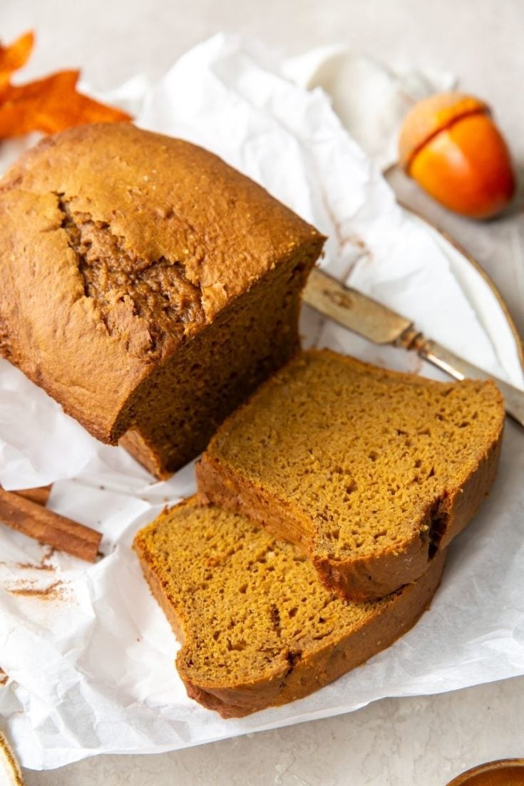 Cake mix pumpkin bread loaf with 2 slices cut laying on parchment paper
