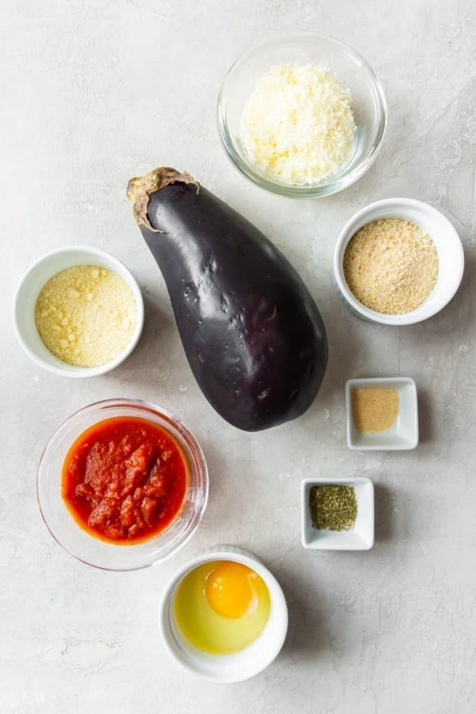 Ingredients needed to make air fryer eggplant parmesan in bowls with a full eggplant in the middle