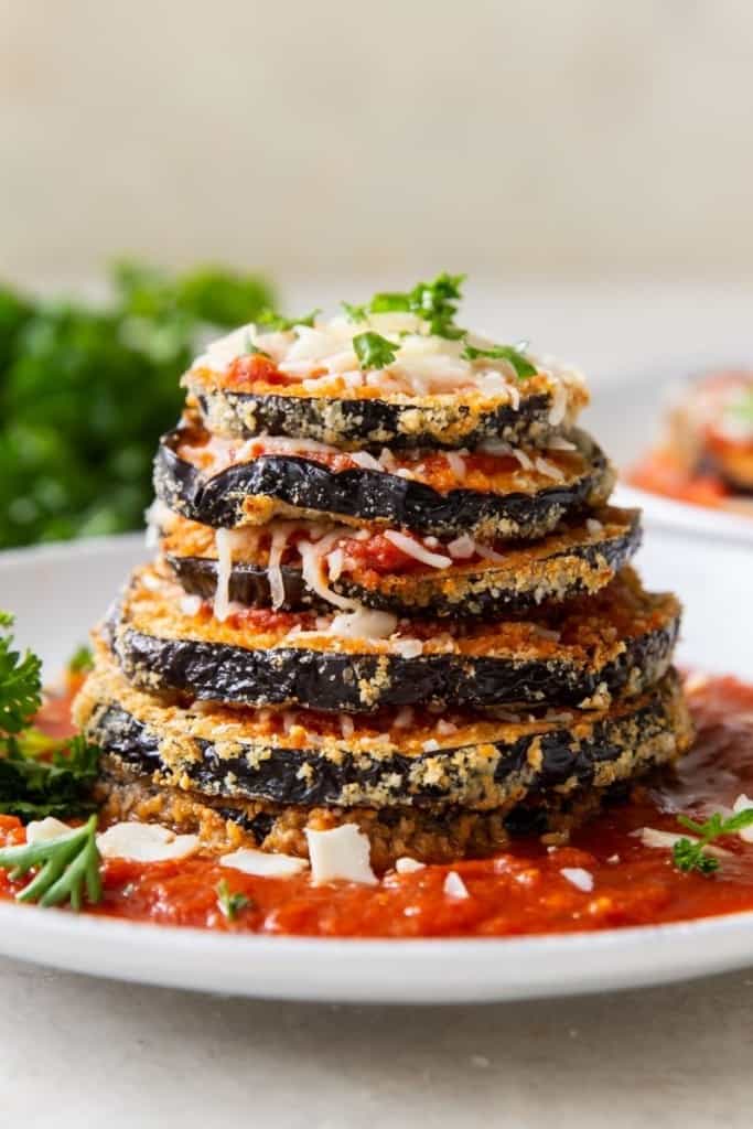 Stacked air fryer eggplant parm on a plate with sauce