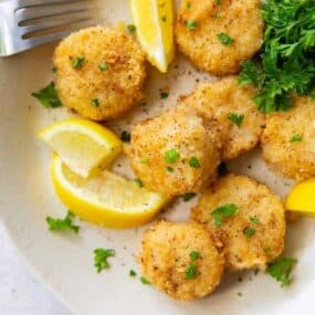 Scallops on a plate with lemon slices and parsley