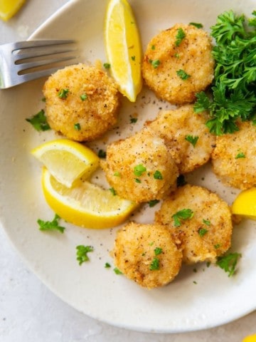 Scallops on a plate with lemon slices and parsley