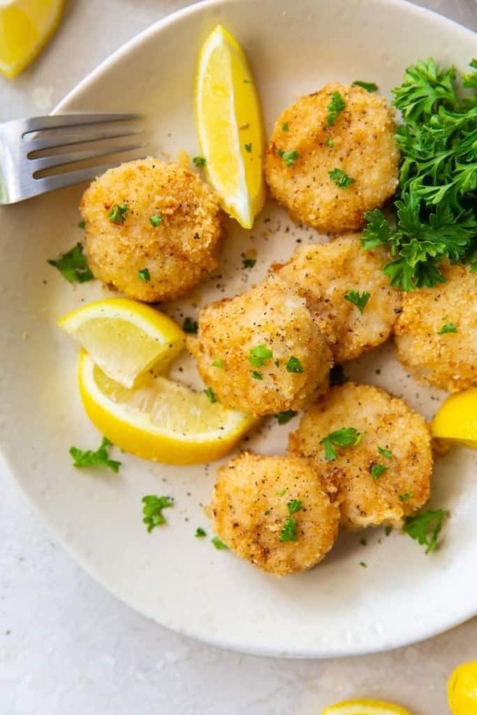 Scallops on a plate with lemon slices and parsley