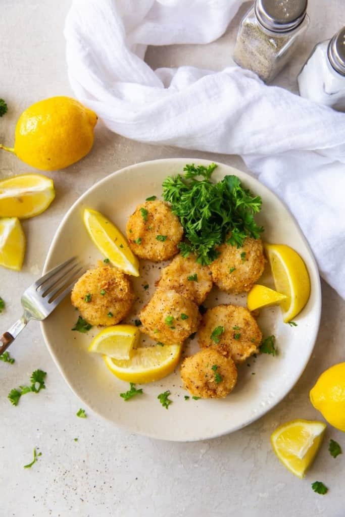 Air Fryer Scallops plated with a fork, lemon slices, and parsley