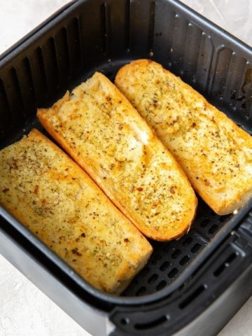 3 halves of garlic bread inside the air fryer cooked