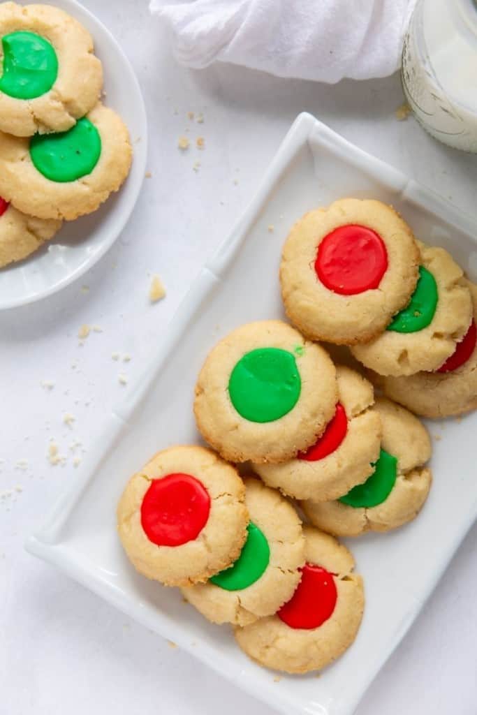 White rectangle plate of red and green thumbprint cookies with icing