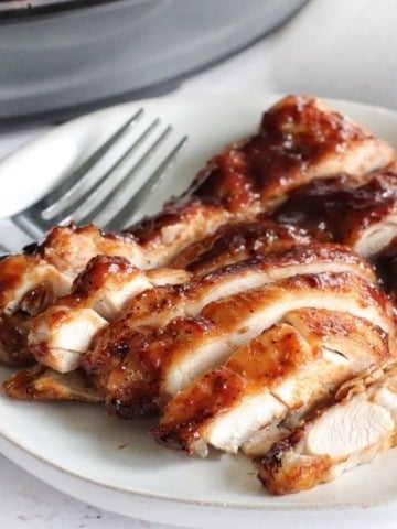Sliced BBQ chicken thighs that were cooked in the Ninja Foodi on a white plate