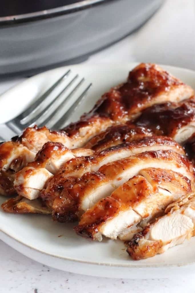 Sliced BBQ chicken thighs that were cooked in the Ninja Foodi on a white plate