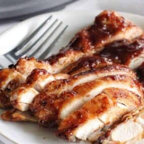 Sliced Ninja Foodi chicken thighs on a plate coated in BBQ sauce