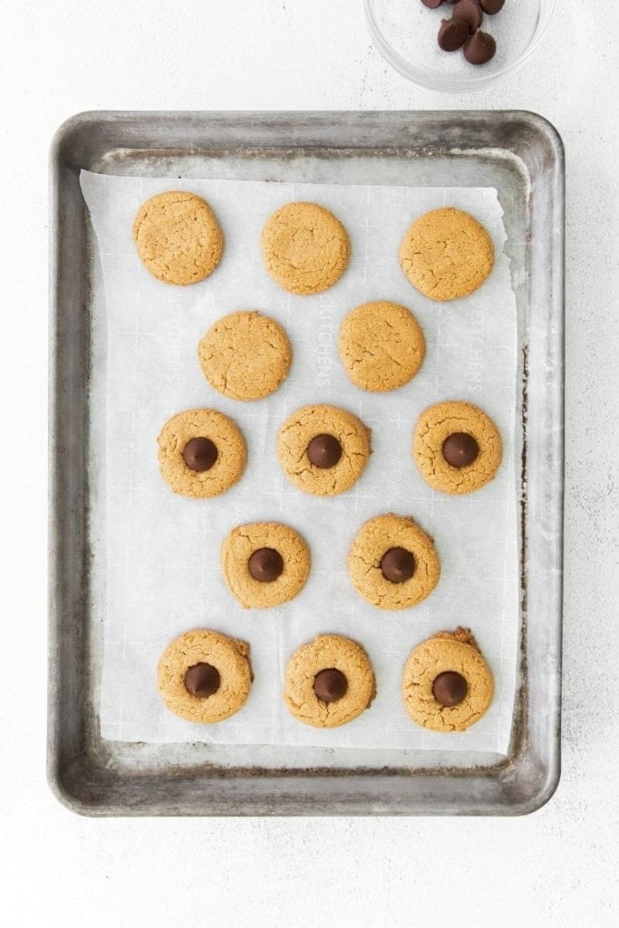 Baked cookies on a baking sheet half topped with Hershey kisses in the middle