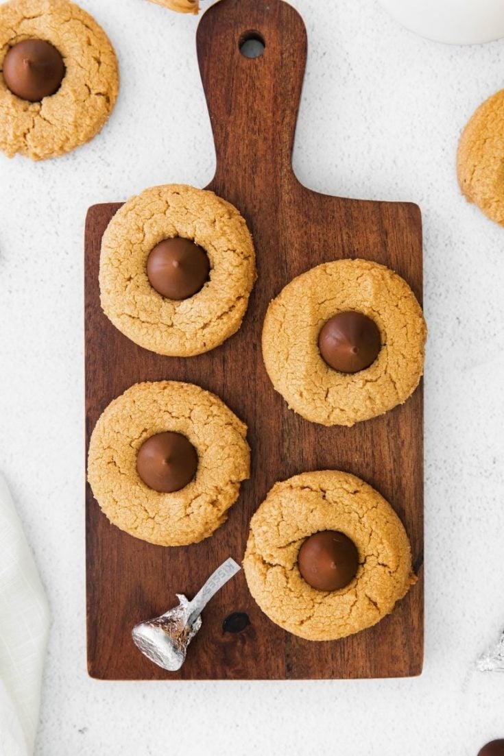 4 Ingredient Peanut Butter Blossoms on a brown cutting board with a Hershey kiss on it