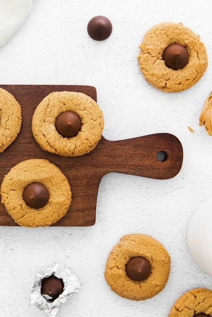 3 Ingredient peanut butter blossoms with Hershey kisses in the middle on a brown cutting board close up