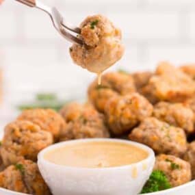 Sausage Balls being dipped in honey mustard on a white serving platter