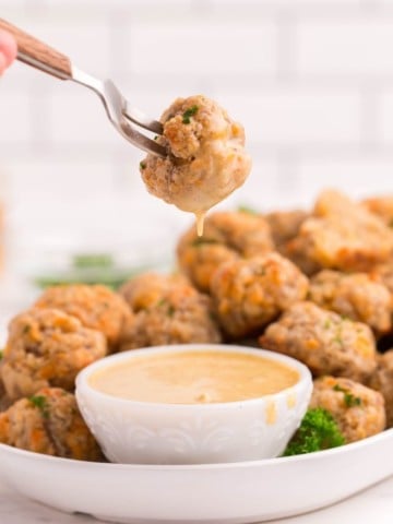 Sausage Balls being dipped in honey mustard on a white serving platter