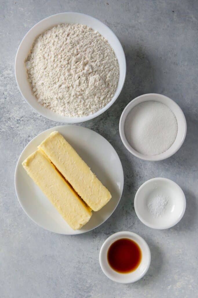 Ingredients needed to make thumbprint cookies with icing: butter, salt, vanilla, flour, salt, powdered sugar, milk, and food coloring.