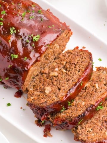 Air Fryer Meatloaf on a white serving tray with half sliced