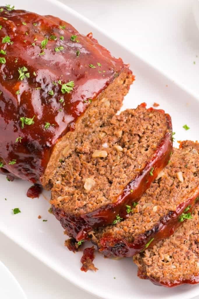 Air Fryer Meatloaf on a white serving tray with half sliced