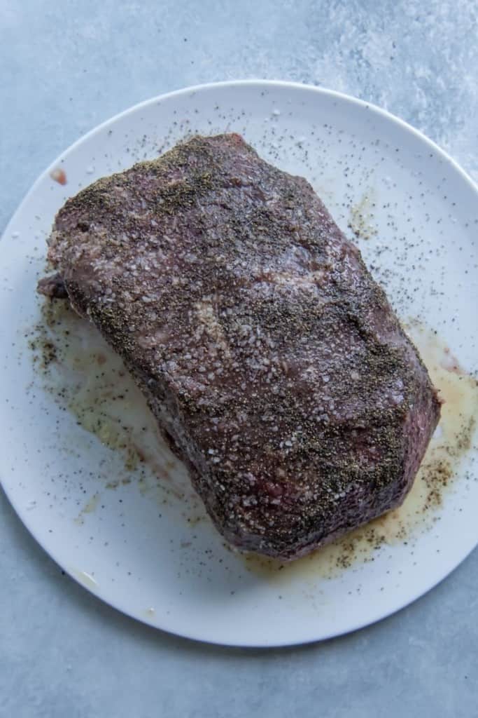 Roast beef sitting to room temperature with salt, pepper, and oil on it