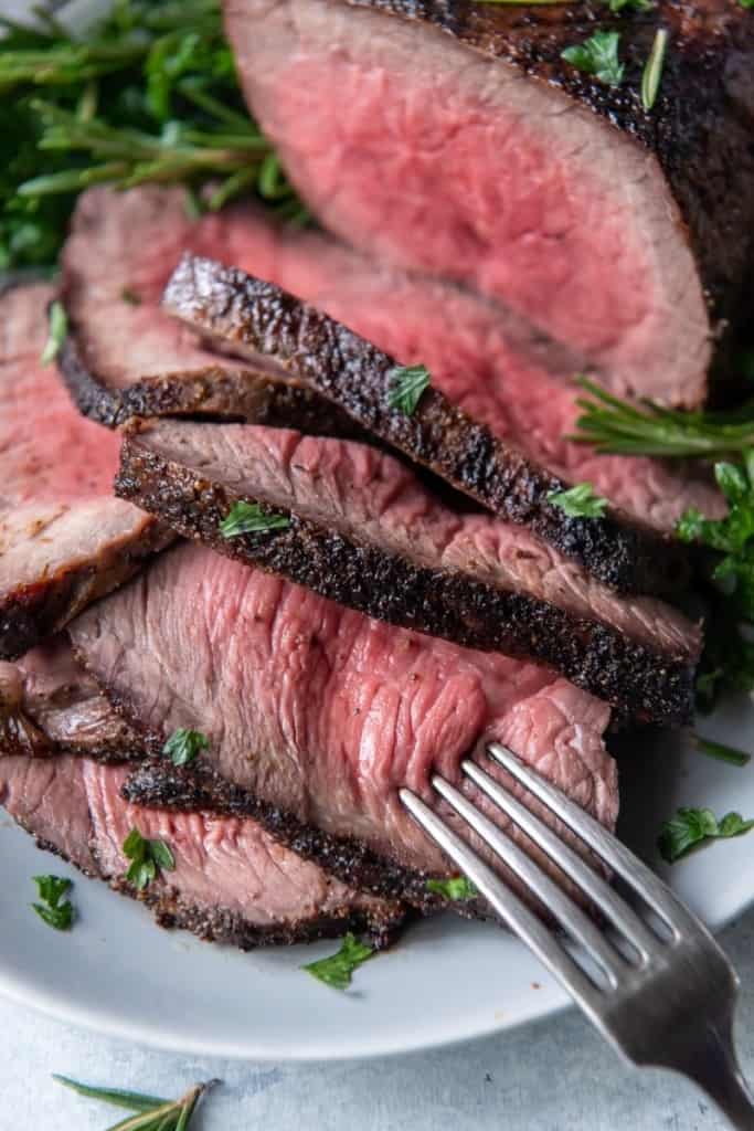 Closeup of medium rare air fryer roast beef sliced with fork in it