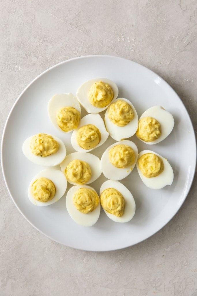 Deviled eggs piped with filling on a round white plate