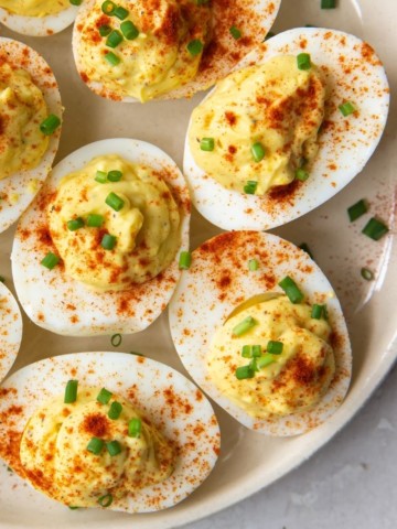 Deviled Eggs with no mustard sprinkled with paprika and chives on a white serving platter