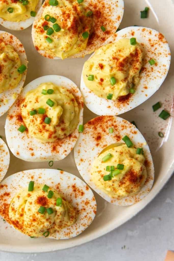 Deviled Eggs with no mustard sprinkled with paprika and chives on a white serving platter