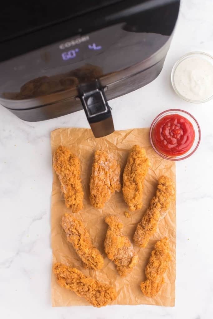 Frozen chicken tenders in front of an air fryer